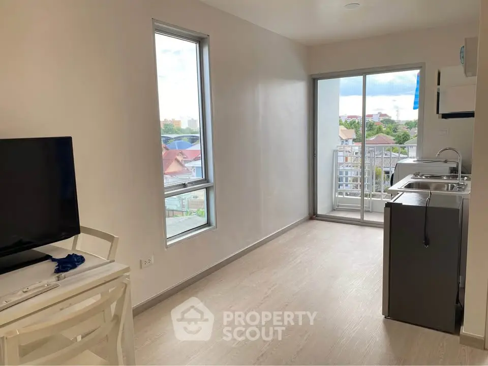 Modern living room with balcony view and sleek kitchen in open layout apartment.