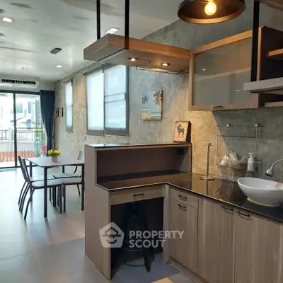 Modern kitchen with open layout and dining area, featuring stylish lighting and contemporary design.