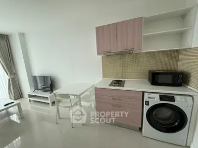Modern studio apartment with compact kitchen and washing machine