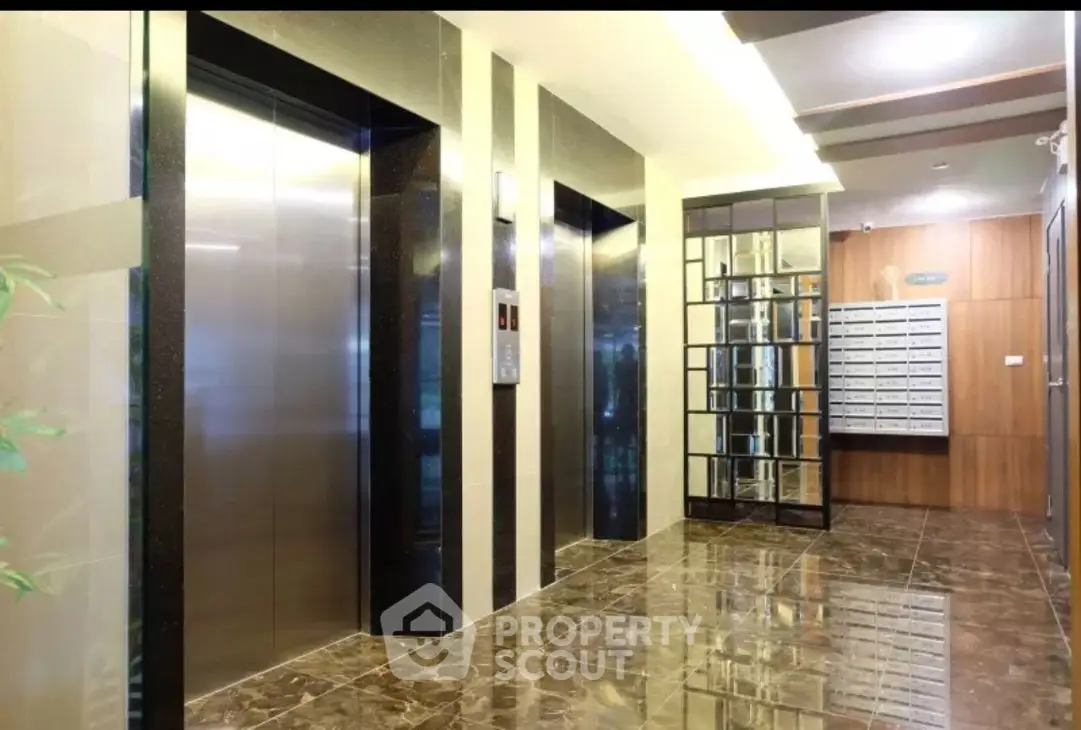 Modern building lobby with elevators and mailboxes, featuring sleek design and polished floors.