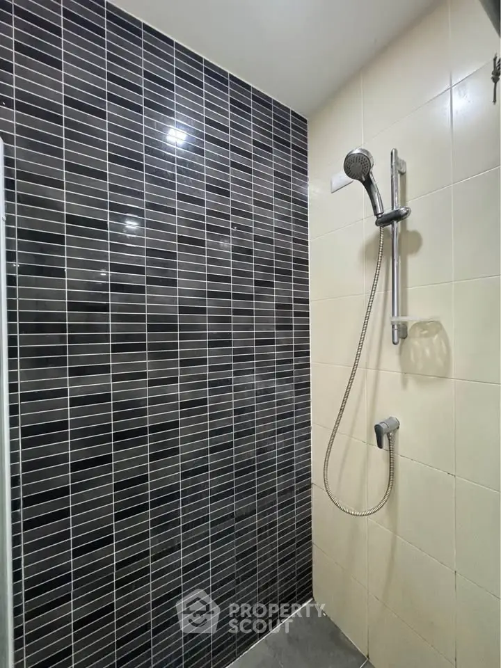Modern bathroom with sleek black and white tiles and a stylish showerhead.