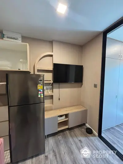 Modern kitchen with sleek fridge and wall-mounted TV in stylish apartment