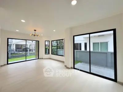 Spacious living room with large windows and modern lighting in a bright, open layout home.