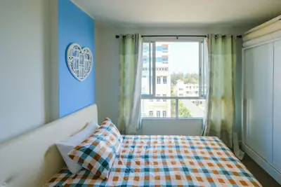 Bright bedroom with large window and colorful bedding in modern apartment