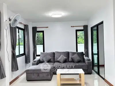 Modern living room with gray sofa and natural light from large windows.