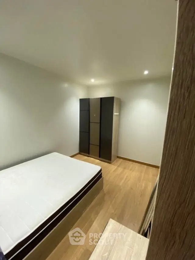 Cozy bedroom with modern minimalist design, featuring a large bed and a sleek wardrobe, perfect for restful nights in a contemporary home.