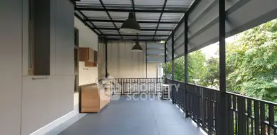 Spacious balcony with modern design and outdoor kitchen overlooking lush greenery.