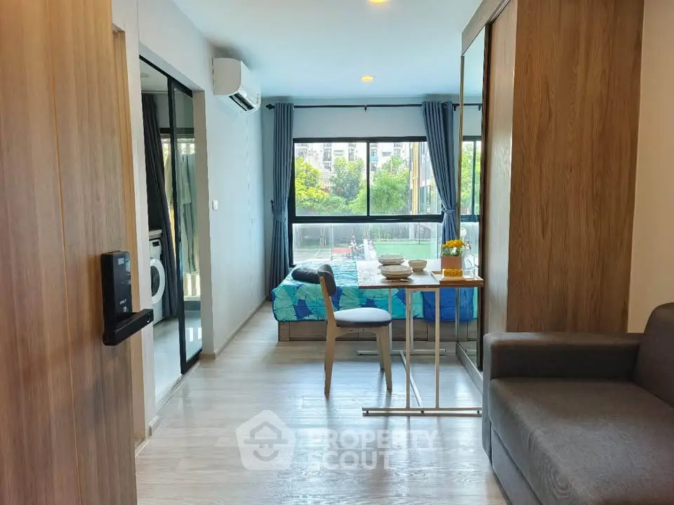 Modern studio apartment with large windows and stylish decor, featuring a cozy living area and compact dining space.