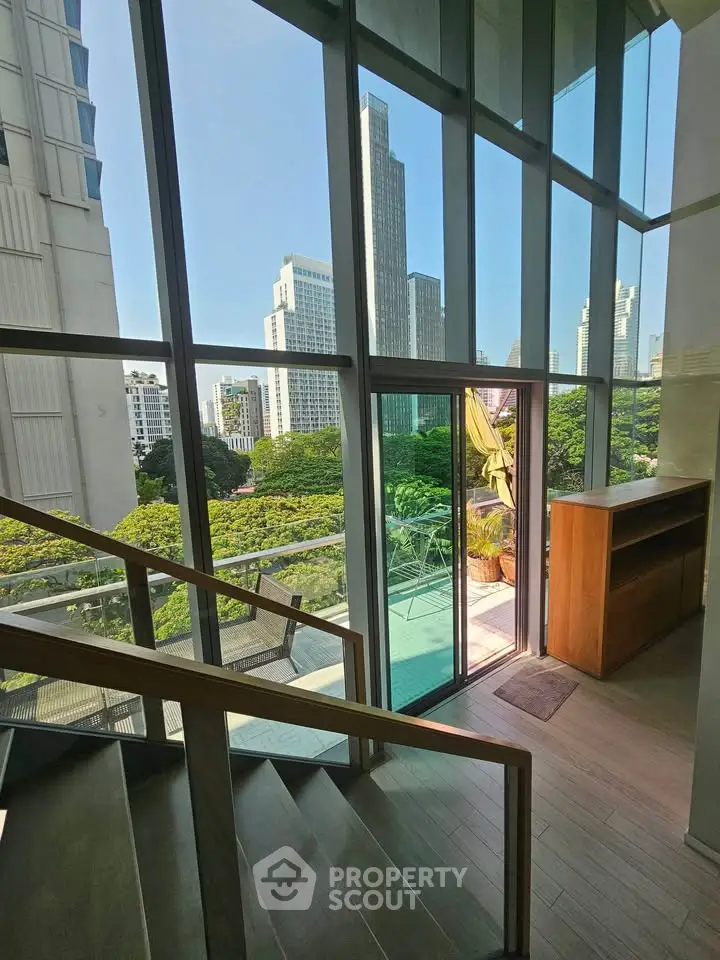 Stunning city view from modern apartment with floor-to-ceiling windows and balcony access.