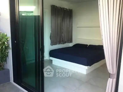 Modern bedroom with large glass doors and elegant curtains, featuring a cozy bed and stylish decor.