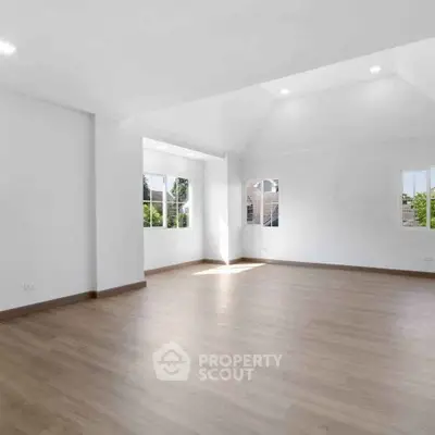 Spacious and bright empty room with large windows and wooden flooring, perfect for customization.