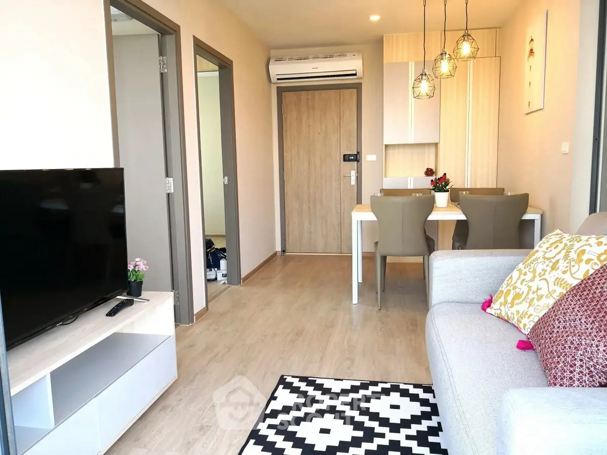 Modern living room with stylish decor and open dining area, featuring a cozy sofa and wall-mounted TV.