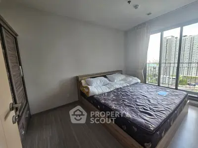 Spacious bedroom with large window offering city view in modern apartment