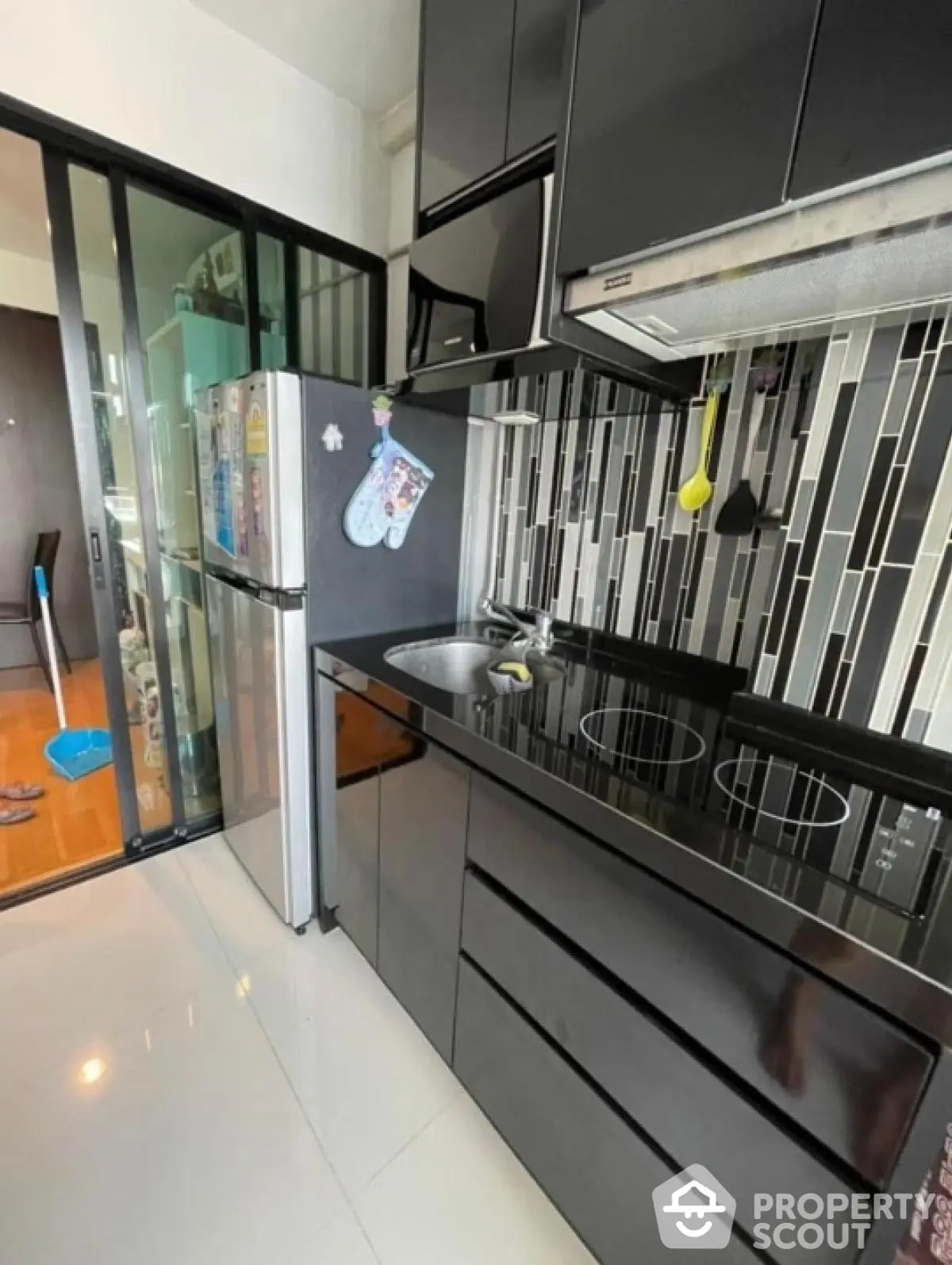 Modern compact kitchen with sleek black cabinets and electric stove