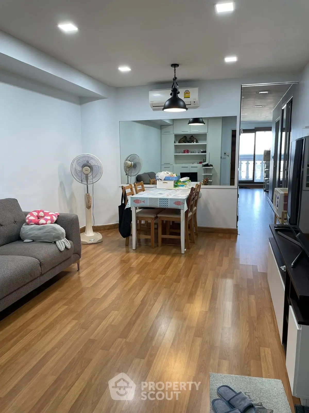Spacious living room with wooden flooring and modern furniture in a cozy apartment.