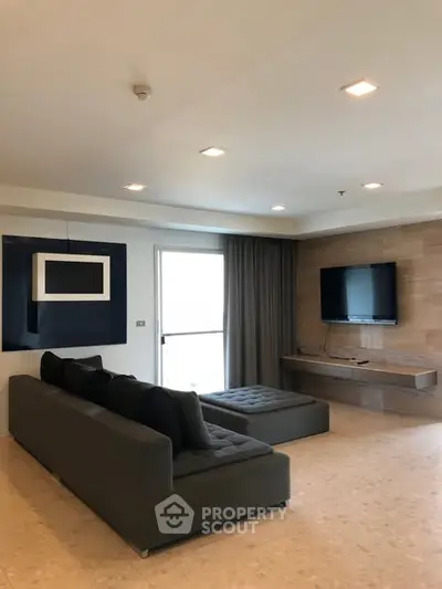 Spacious modern living room with sleek furniture and wall-mounted TV, perfect for relaxation and entertainment.