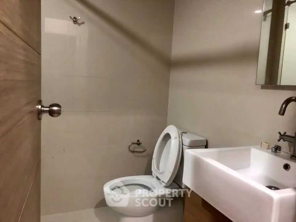Modern bathroom with sleek fixtures and neutral tones, featuring a toilet and sink.