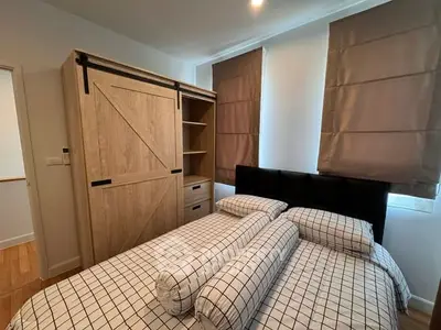 Cozy bedroom with modern wooden wardrobe and stylish bedding