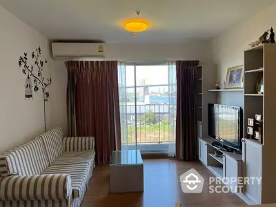 Inviting living room with striped sofa set, gleaming floors, and ample natural light streaming through large windows, offering a cozy urban retreat.