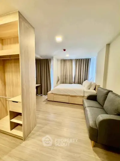 Modern studio apartment with cozy bed, stylish sofa, and wooden flooring, perfect for urban living.