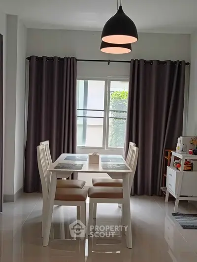 Modern dining area with elegant lighting and natural light from large window.