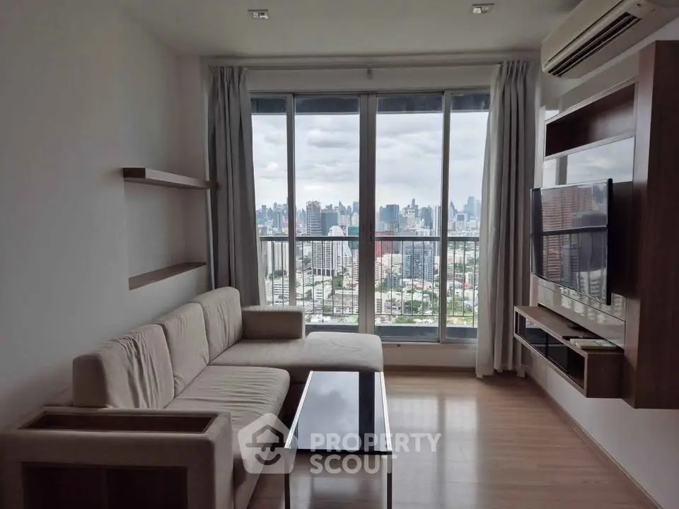 Modern living room with city view, featuring sleek furniture and large windows for natural light.