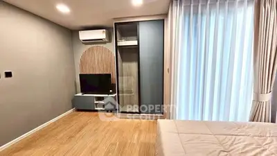 Modern bedroom with stylish decor, featuring a sleek wardrobe and natural light from large windows.