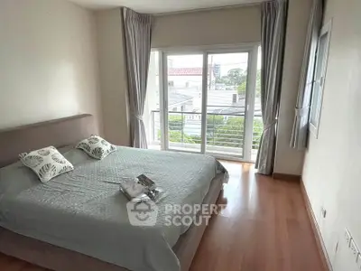 Spacious bedroom with large window and balcony access, offering a serene view and natural light.