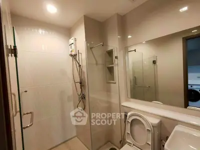 Modern bathroom with glass shower enclosure and sleek fixtures in a contemporary apartment.