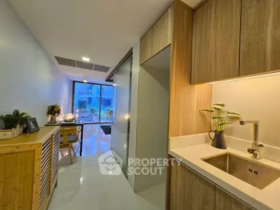 Modern apartment interior with sleek kitchen and dining area, featuring stylish decor and natural lighting.