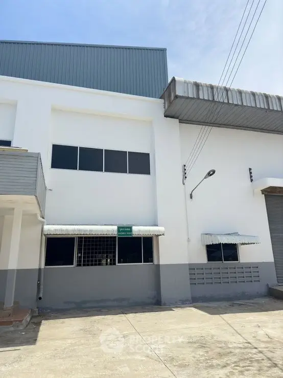 Modern industrial building exterior with large windows and loading dock.