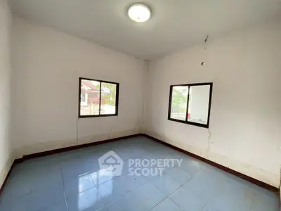 Spacious empty room with tiled floor and large windows offering natural light.