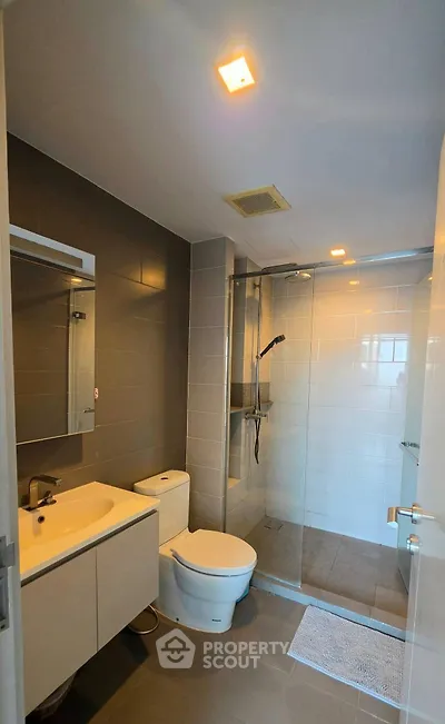 Modern bathroom with sleek design, featuring a glass-enclosed shower and contemporary fixtures.