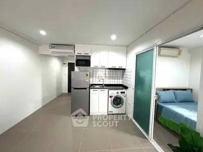 Modern apartment kitchen with washing machine and adjacent bedroom