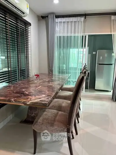 Modern dining area with marble table and elegant chairs, adjacent to a sleek kitchen with stainless steel fridge.
