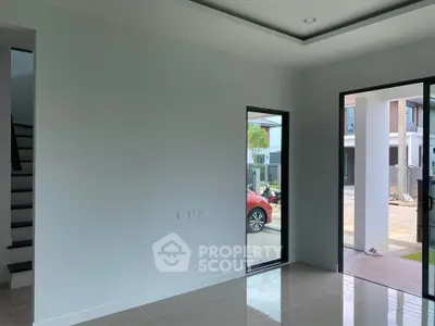 Spacious modern interior with large windows and sleek tile flooring, offering a glimpse of the outdoor area.