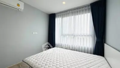 Bright bedroom with large window and modern air conditioning unit, perfect for cozy living.
