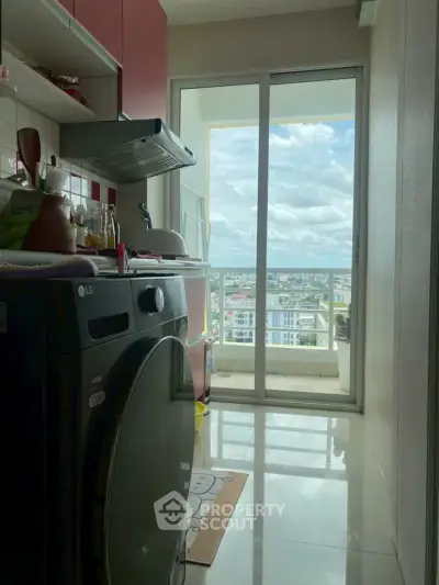 Compact kitchen with washing machine and balcony view in modern apartment