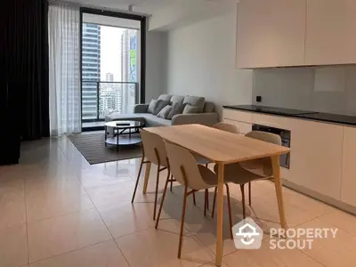 Modern apartment with open-plan layout featuring a sleek kitchen, spacious dining area, and cozy living space leading to a sunny balcony.