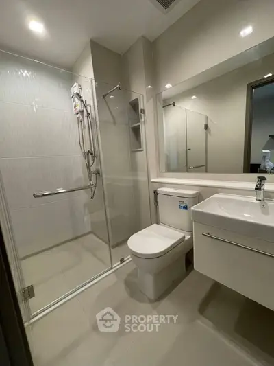 Modern bathroom with glass shower enclosure and sleek fixtures in a contemporary apartment.