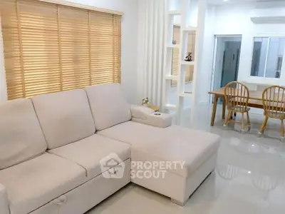Spacious living room with modern beige sofa and dining area, perfect for cozy family gatherings.