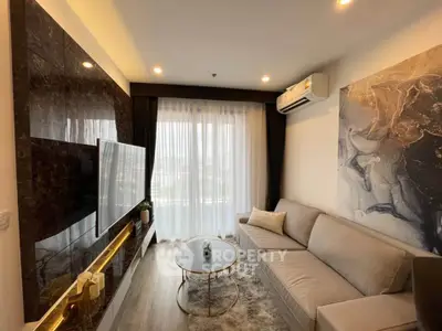 Modern living room with stylish decor, large TV, and cozy seating area.
