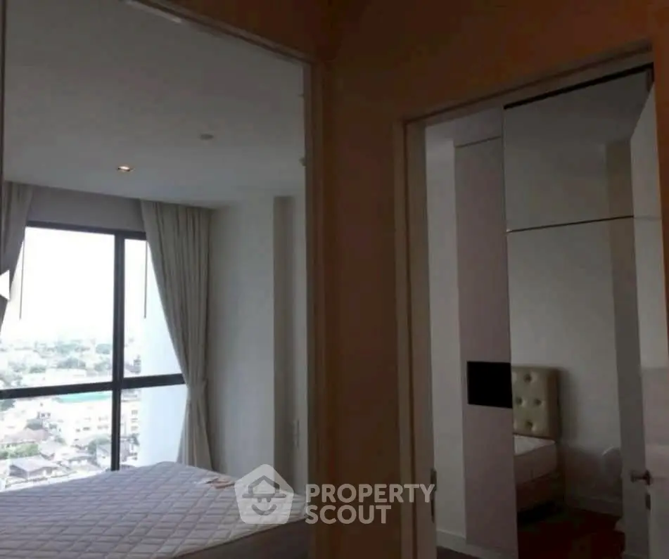 Spacious bedroom with large window offering city views and modern decor.