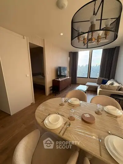 Modern living room with dining area and city view, featuring elegant decor and natural light.