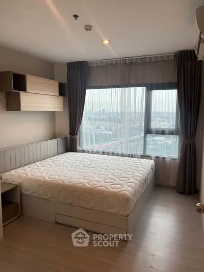 Modern bedroom with large window and stylish decor in high-rise apartment.
