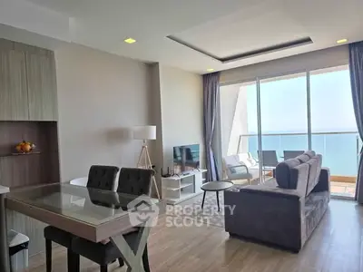 Modern living room with ocean view, stylish furniture, and large windows leading to a balcony.