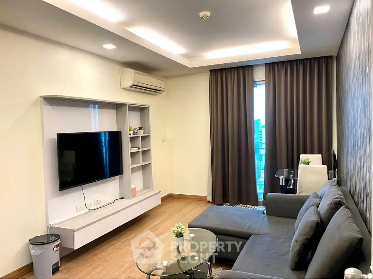 Modern living room with sleek furniture and large TV, featuring a cozy ambiance.