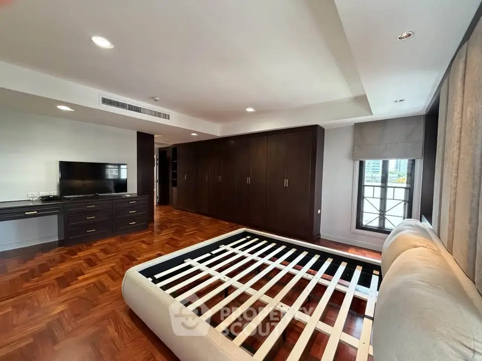 Spacious bedroom with wooden flooring and large wardrobe in modern apartment