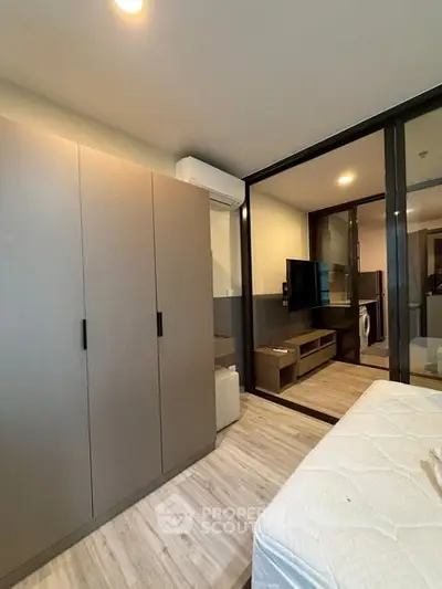 Modern bedroom with sleek wardrobe and glass partition, featuring a cozy ambiance and stylish flooring.