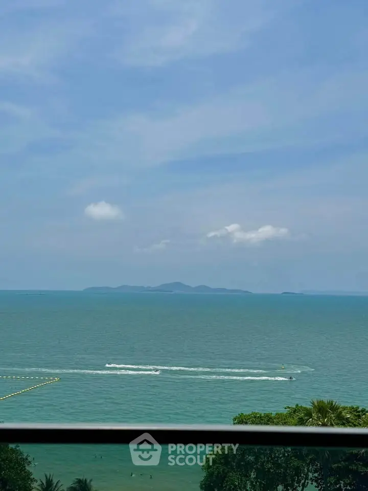Stunning ocean view from a high-rise balcony with clear blue skies and distant islands.